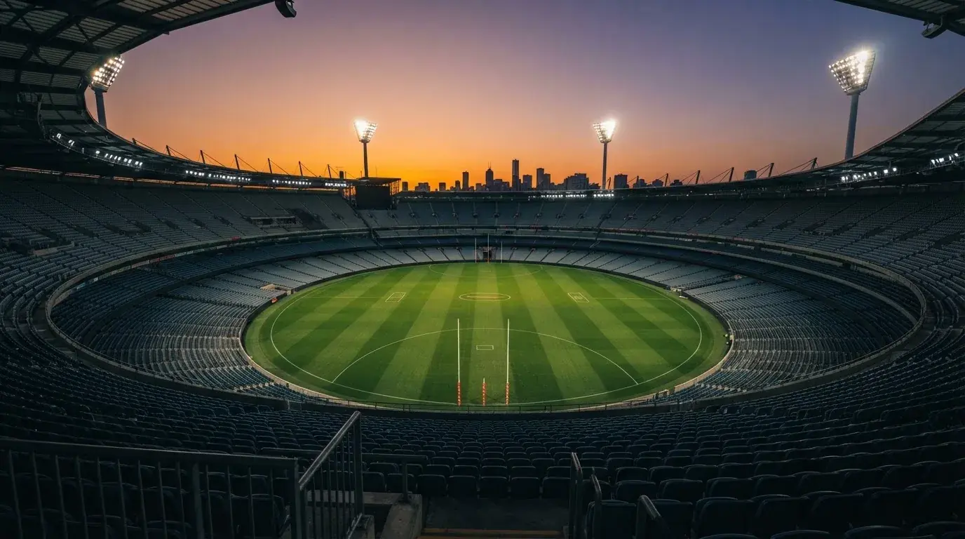 An empty football stadium with floodlight masts at dusk