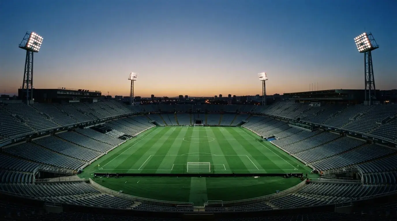 An empty football stadium with floodlight masts at dusk