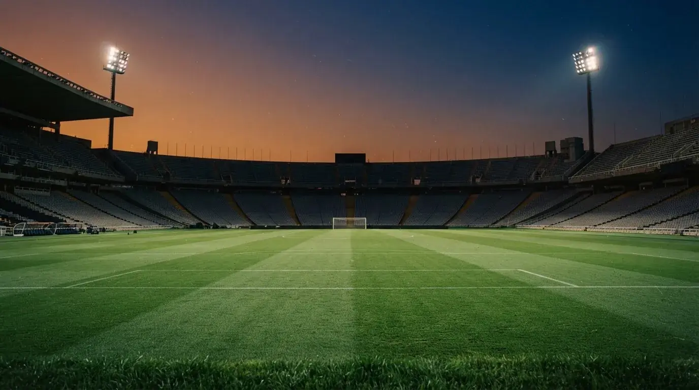 An empty football stadium with floodlight masts at dusk