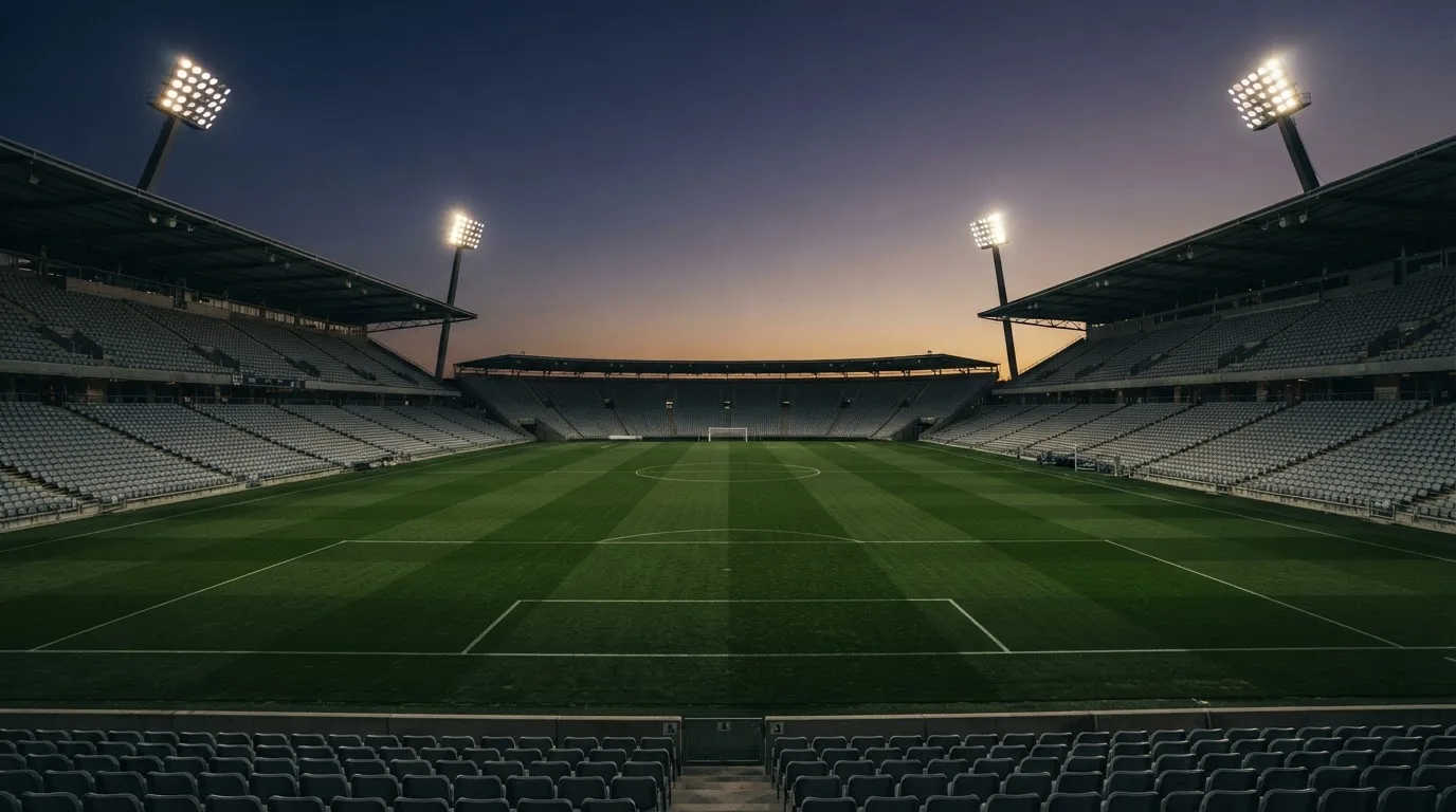 An empty football stadium with floodlight masts at dusk