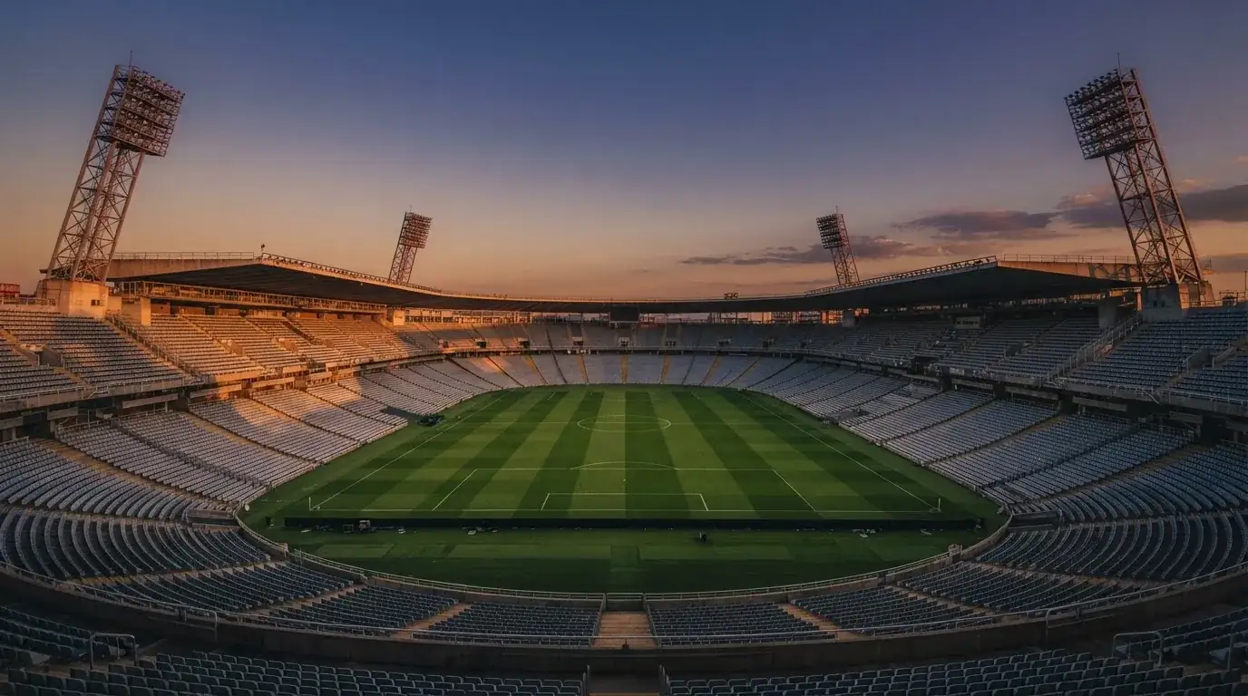 An empty football stadium with floodlight masts at dusk