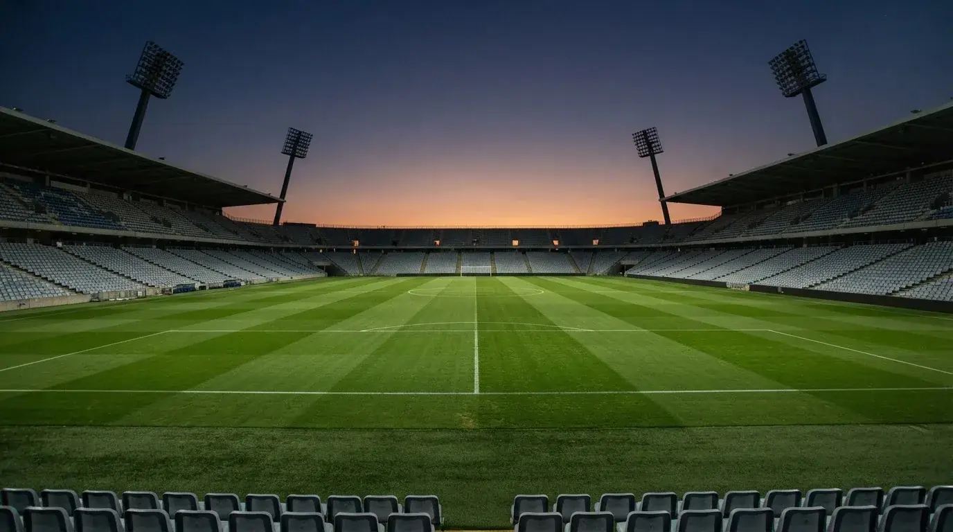 An empty football stadium with floodlight masts at dusk