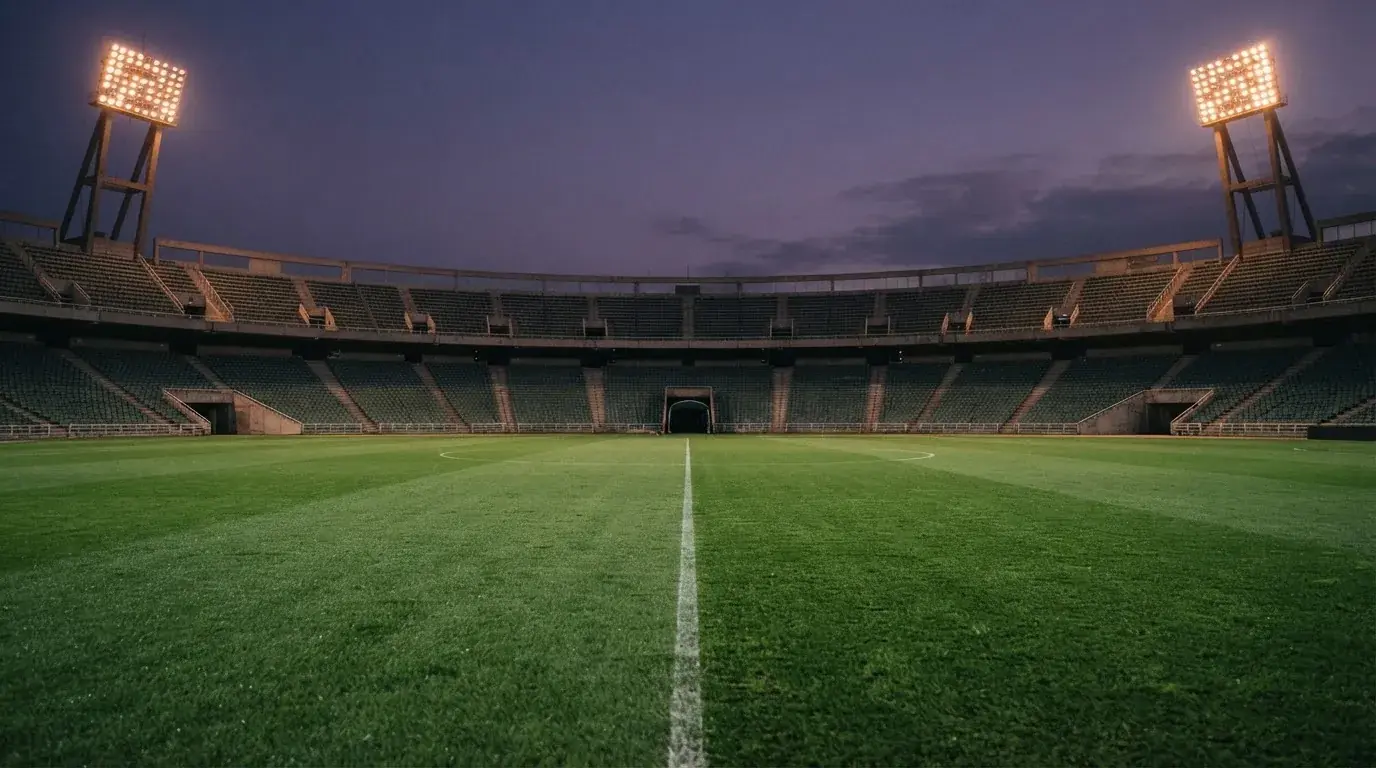 An empty football stadium with floodlight masts at dusk