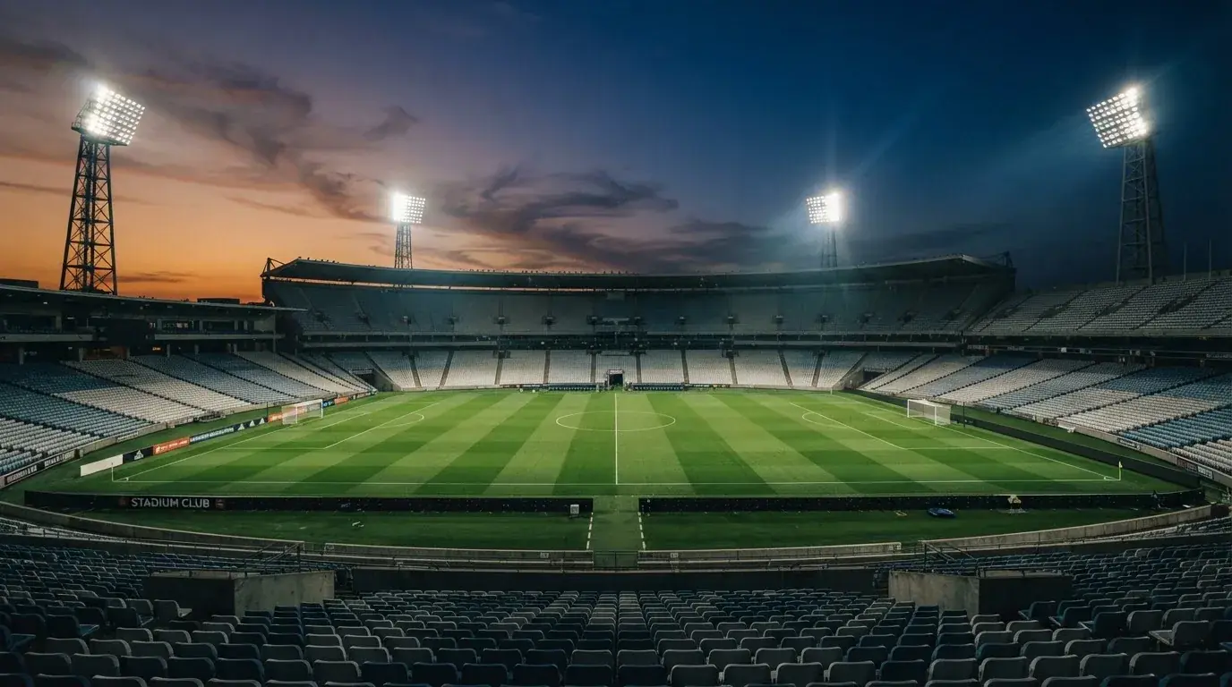 An empty football stadium with floodlight masts at dusk