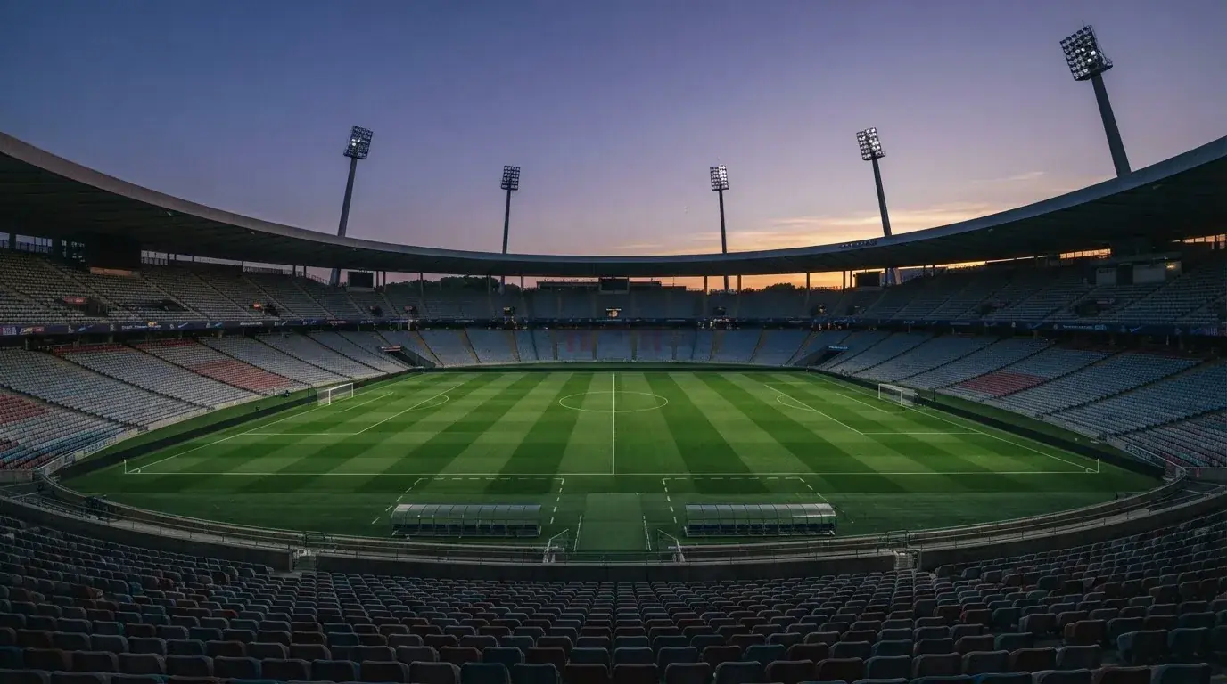 An empty football stadium with floodlight masts at dusk