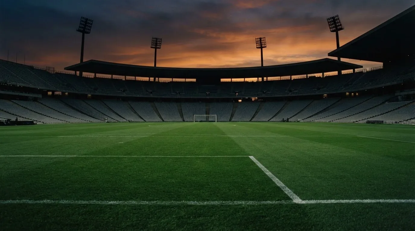 An empty football stadium with floodlight masts at dusk