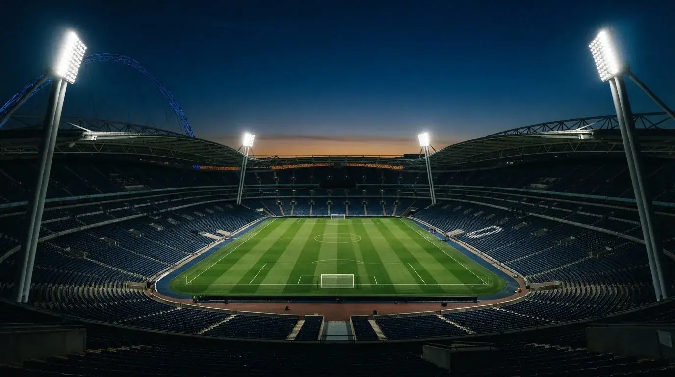 An empty football stadium with floodlight masts at dusk