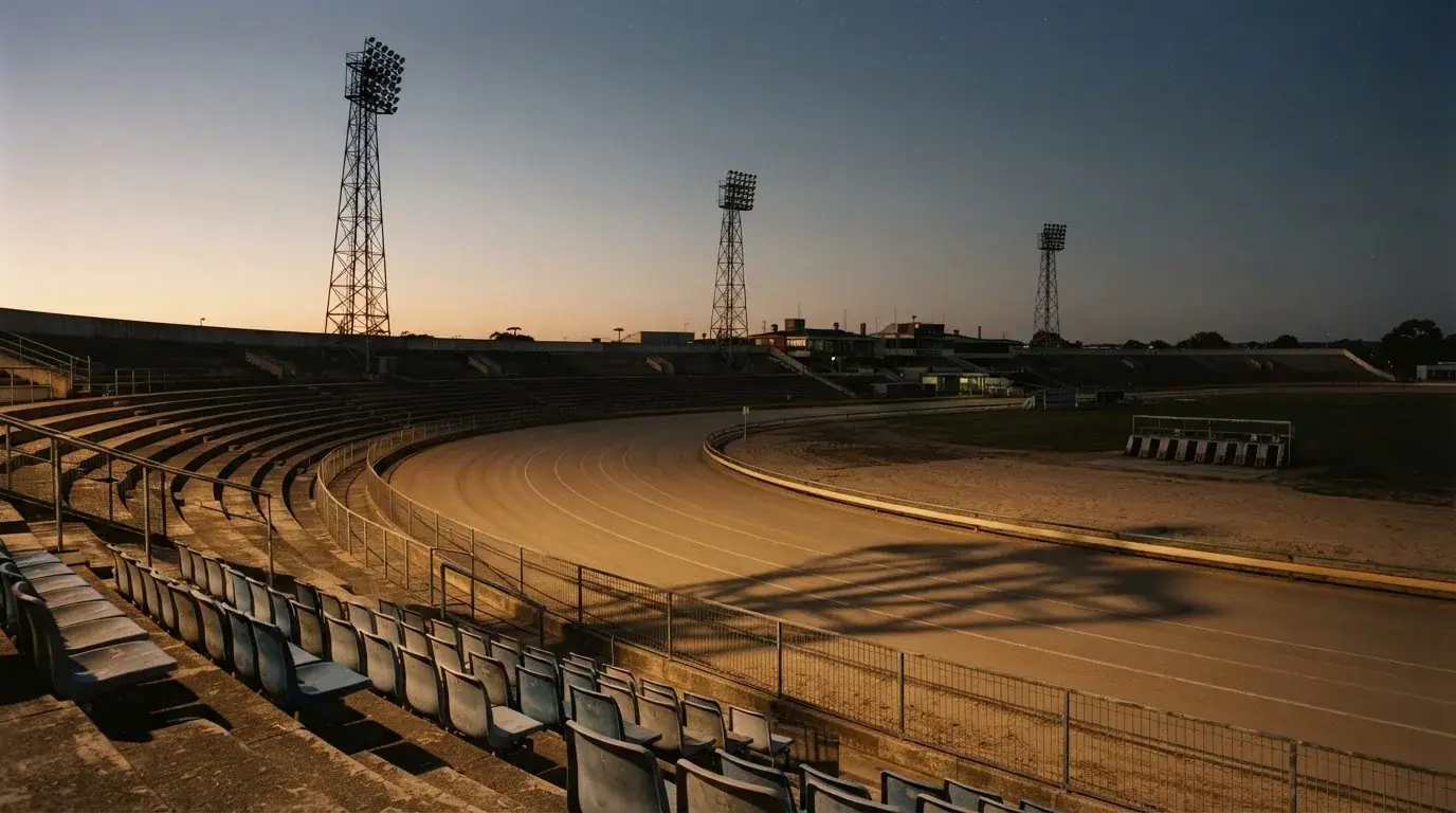 An empty football stadium with floodlight masts at dusk