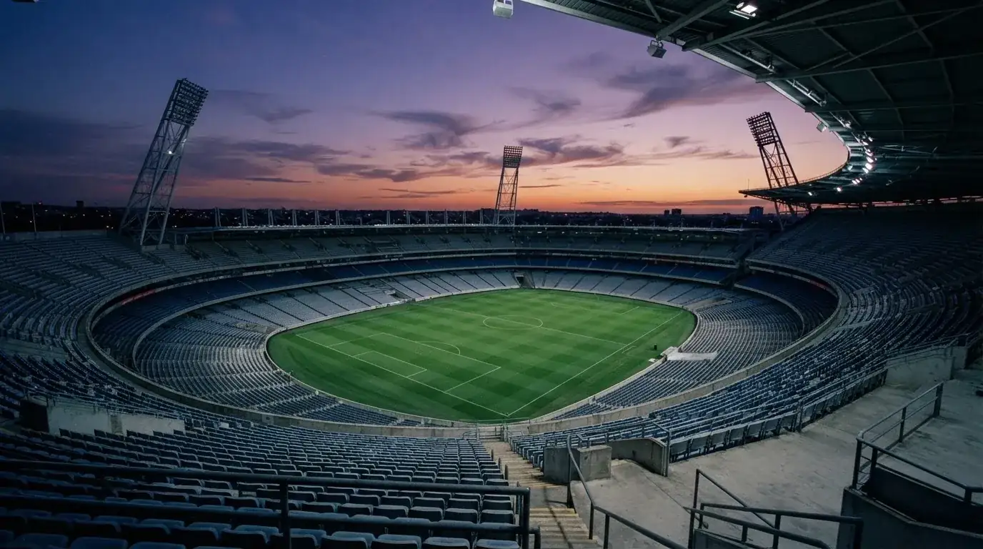 An empty football stadium with floodlight masts at dusk