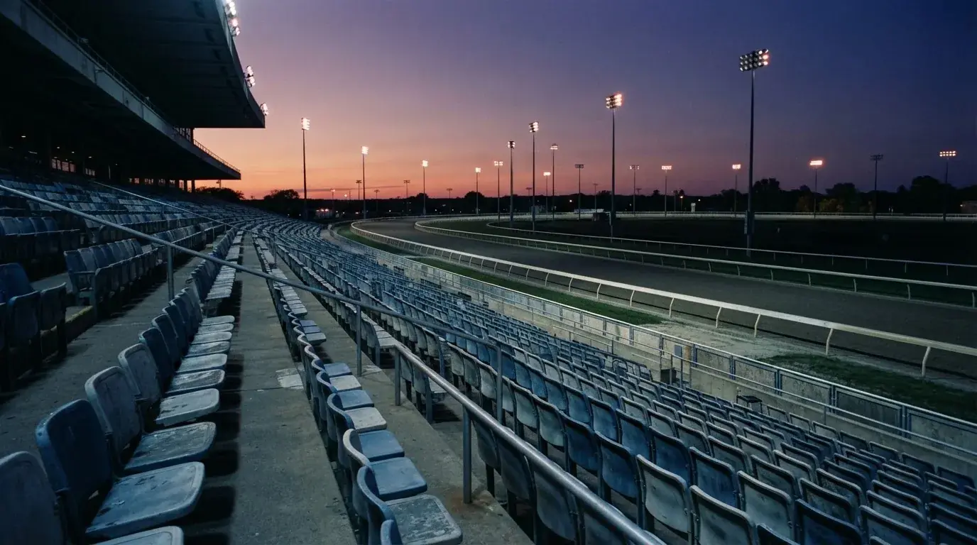 An empty football stadium with floodlight masts at dusk