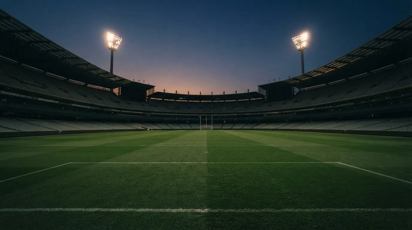 An empty football stadium with floodlight masts at dusk