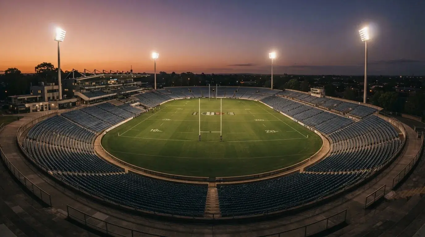 An empty football stadium with floodlight masts at dusk
