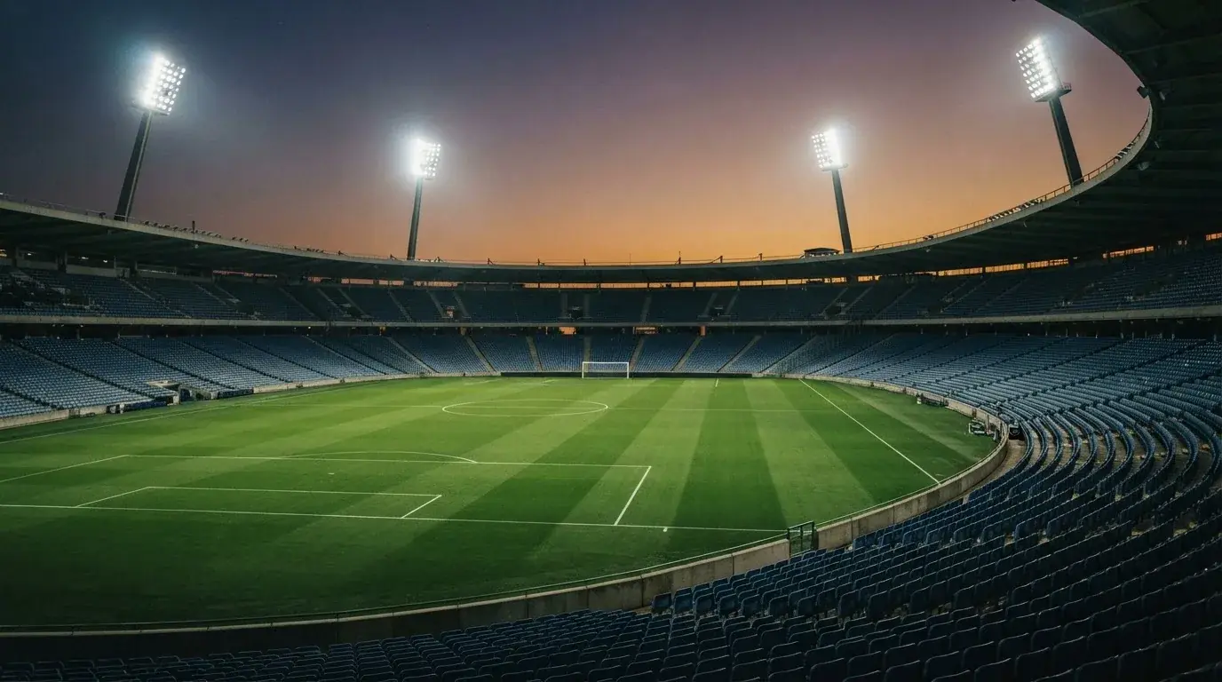 An empty football stadium with floodlight masts at dusk