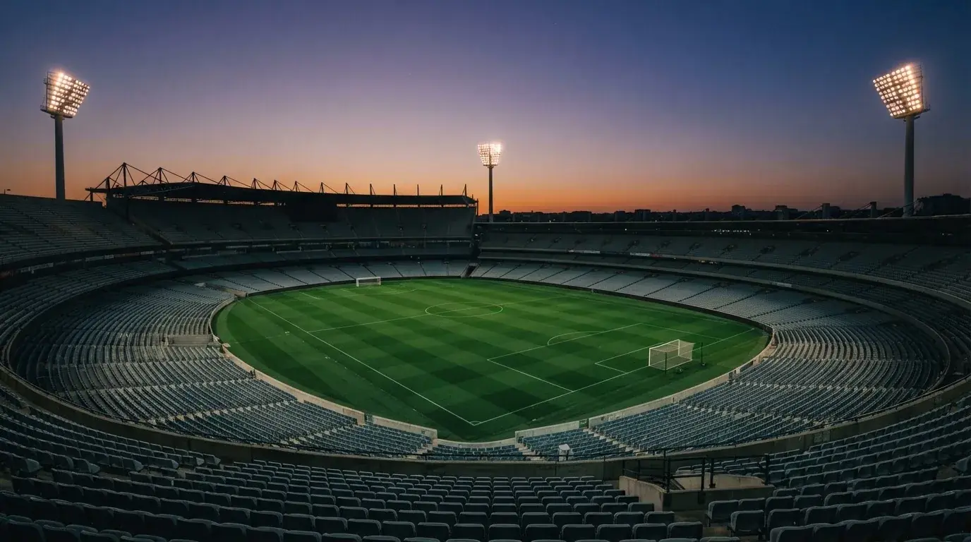 An empty football stadium with floodlight masts at dusk