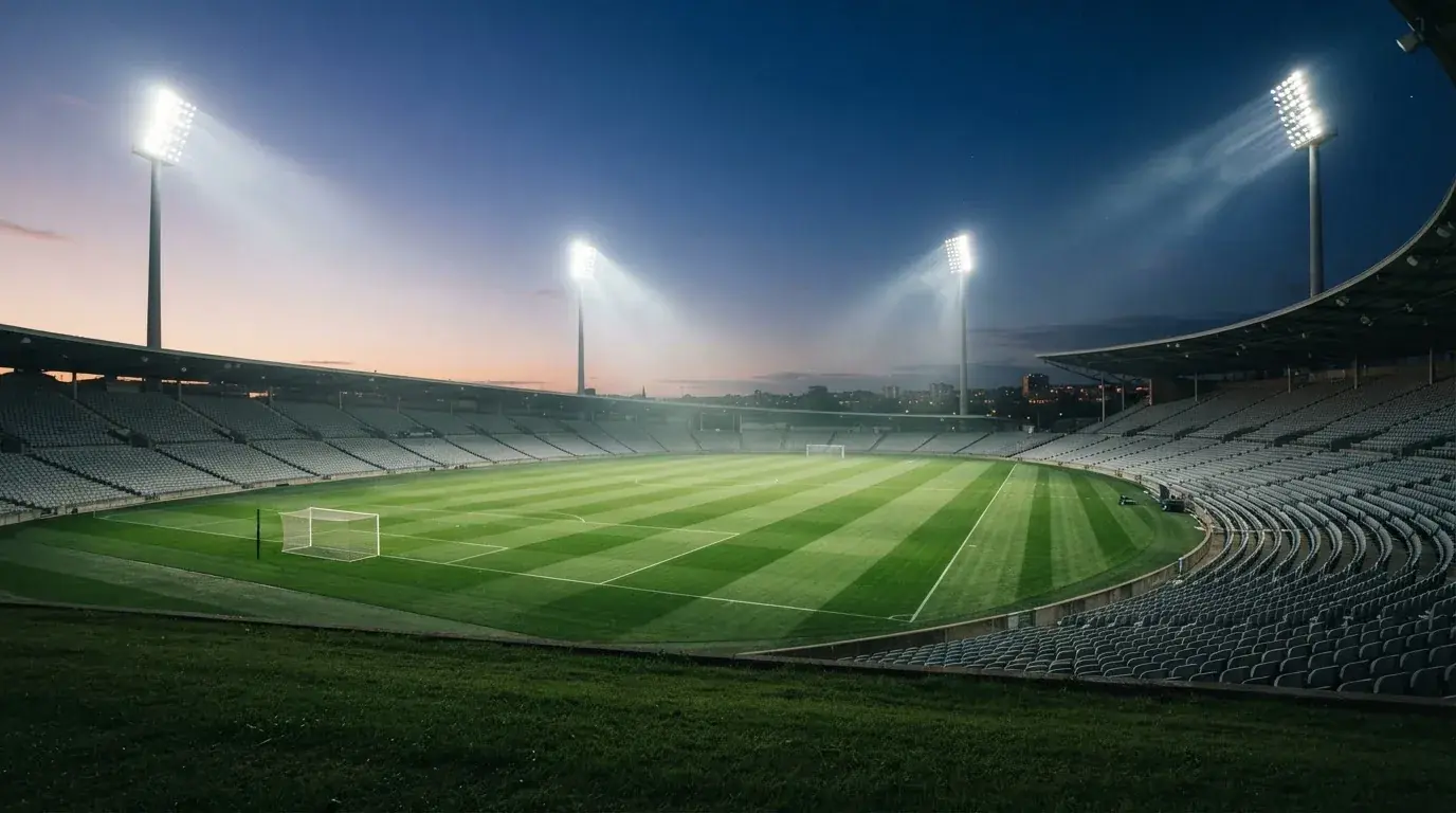 An empty football stadium with floodlight masts at dusk